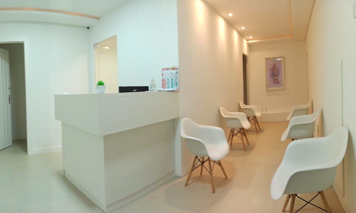 Recepção da Foco X em Florianópolis, com balcão branco e cadeiras de espera